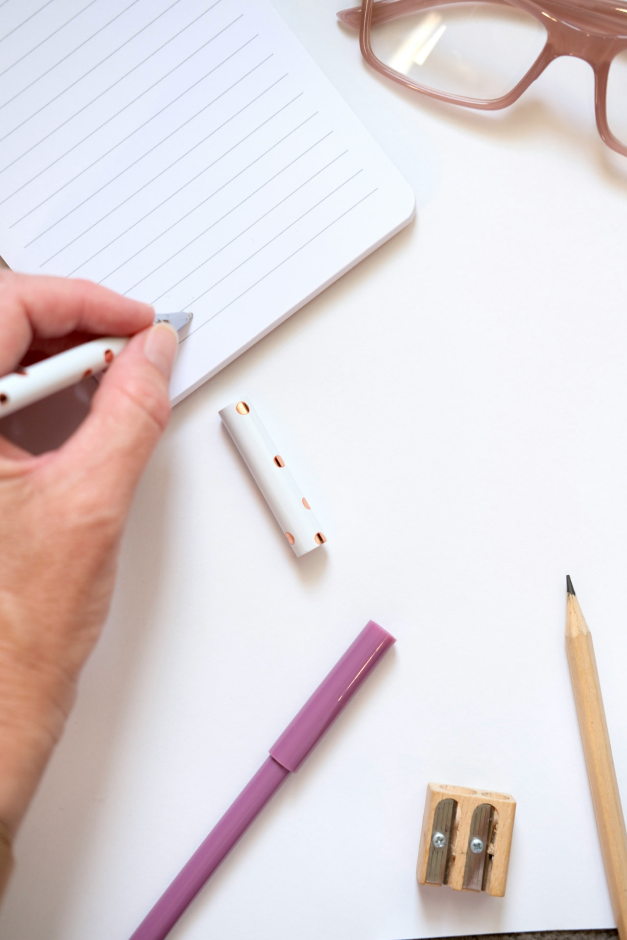 Hand writing notes on a notepad at a desk